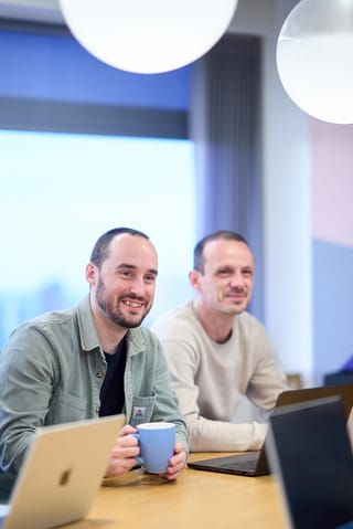 Lee, Ryan and Tom reviewing work together on a laptop at a conference table.