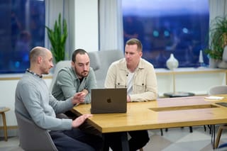 Lee, Ryan and Tom reviewing work together on a laptop at a conference table.