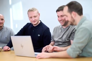 Lee, Ryan and Tom reviewing work together on a laptop at a conference table.